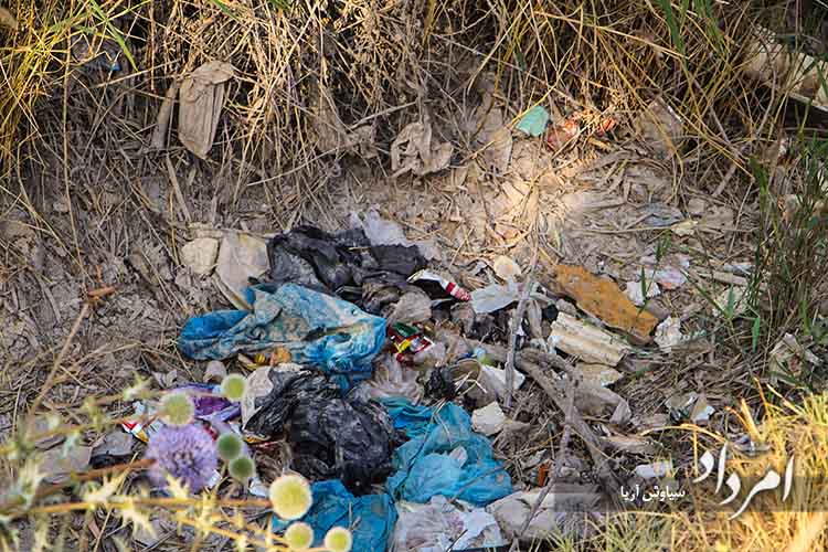 انبوه زباله های پلاستیکی و خانگی که در کف چشمه خشکیده برم دلک ریخته شده و صحنه زشتی را به نمایش گذاشته است copy